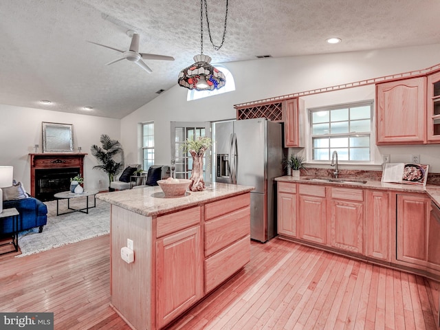 kitchen with a sink, stainless steel fridge with ice dispenser, a textured ceiling, light wood-style floors, and lofted ceiling