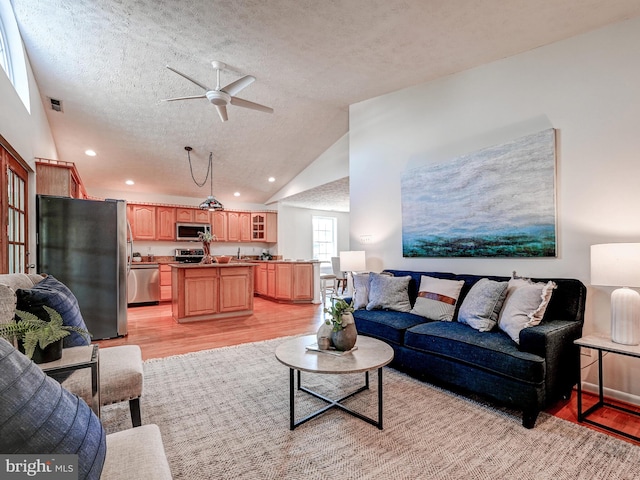 living room featuring light wood-style floors, a ceiling fan, a textured ceiling, high vaulted ceiling, and recessed lighting