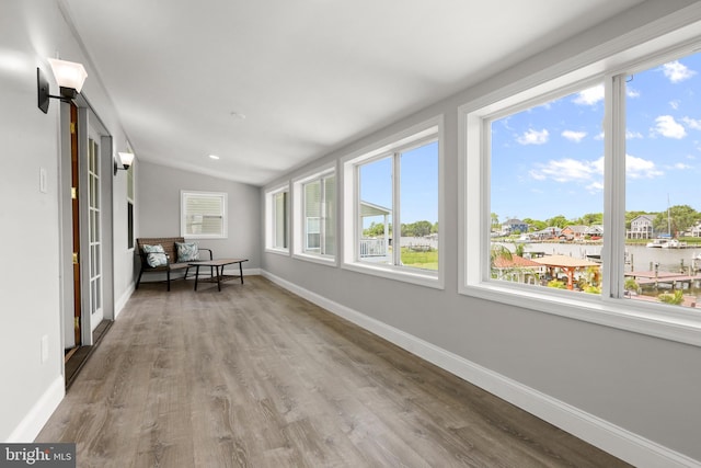 sunroom / solarium featuring wood finished floors, baseboards, and lofted ceiling