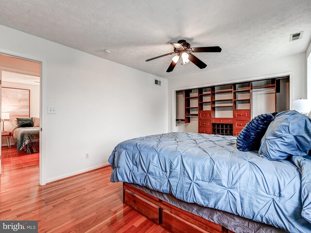 bedroom with wood finished floors, baseboards, a textured ceiling, and a ceiling fan