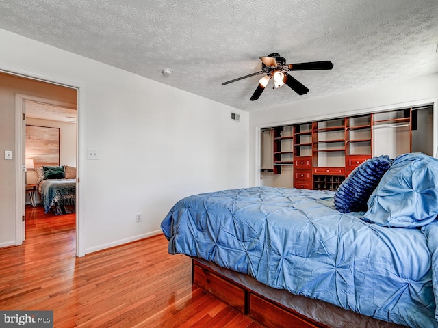 bedroom with wood finished floors, baseboards, a textured ceiling, and a ceiling fan