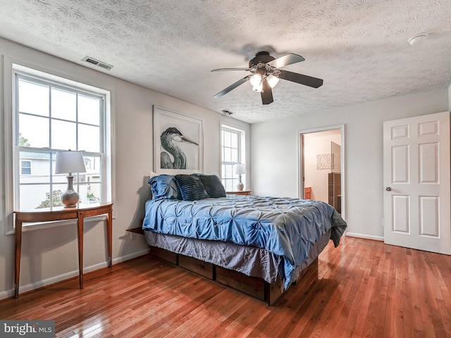 bedroom with baseboards, hardwood / wood-style floors, a textured ceiling, and a ceiling fan