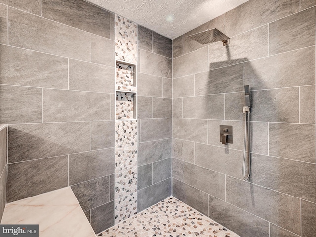 full bath featuring tiled shower and a textured ceiling