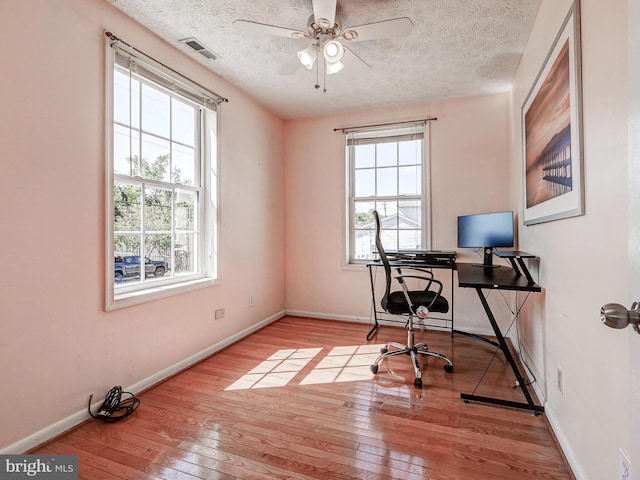 office space featuring hardwood / wood-style flooring, ceiling fan, baseboards, and a textured ceiling