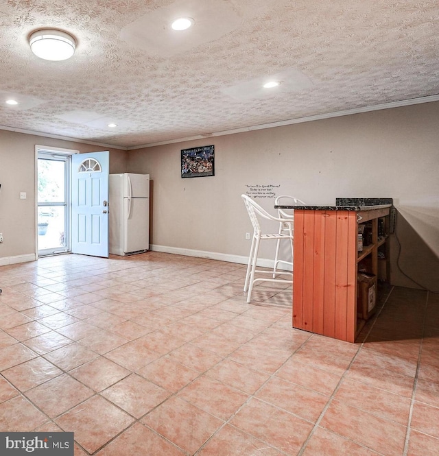 kitchen featuring freestanding refrigerator, ornamental molding, baseboards, dark countertops, and recessed lighting