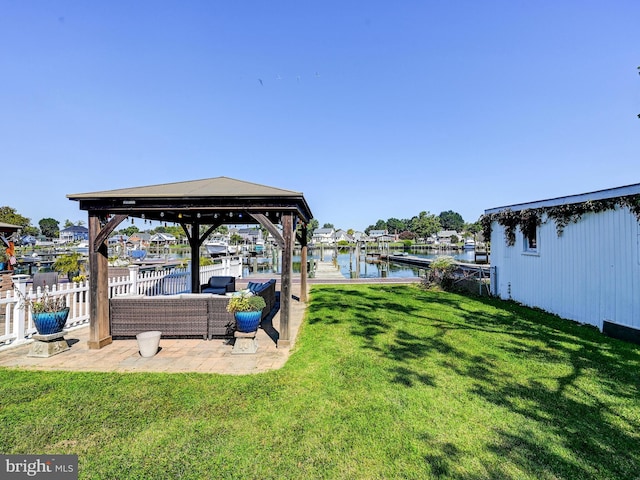 view of grassy yard with a water view, a gazebo, a dock, and a patio area