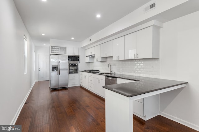 2514 Ashland Ave, Baltimore, MD 21205 - kitchen featuring appliances with stainless steel finishes, a sink, a peninsula, dark countertops, and decorative backsplash
