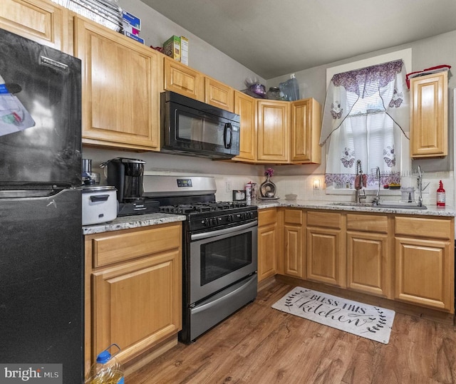 2022 Rowan St, Philadelphia, PA 19140 - kitchen with black appliances, a sink, wood finished floors, and light stone countertops