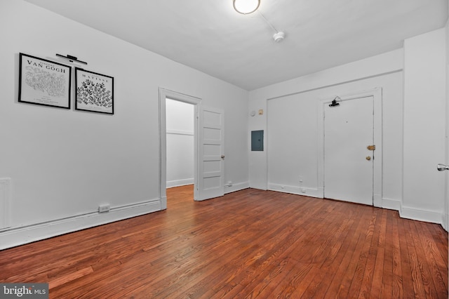 unfurnished bedroom featuring hardwood / wood-style flooring, electric panel, baseboards, and a closet