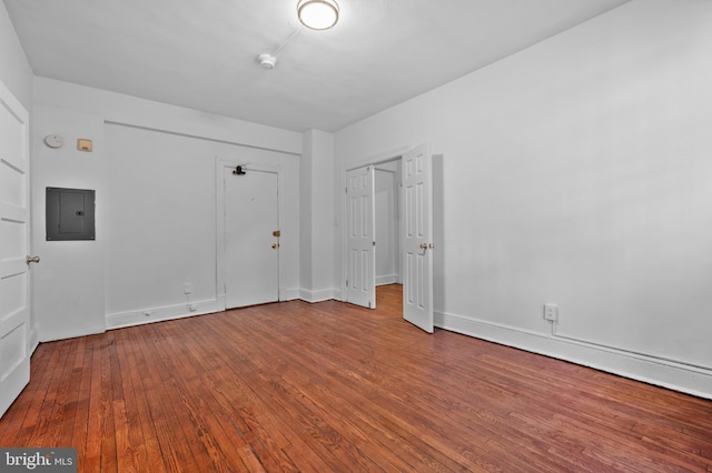 unfurnished bedroom featuring electric panel, wood-type flooring, and baseboards