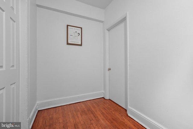 hall with wood-type flooring and baseboards