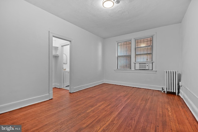 spare room with radiator, hardwood / wood-style flooring, cooling unit, baseboards, and a textured ceiling
