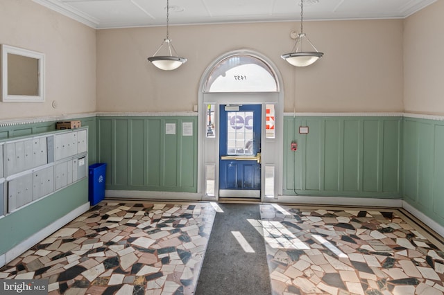 foyer entrance featuring a wainscoted wall, crown molding, and a decorative wall