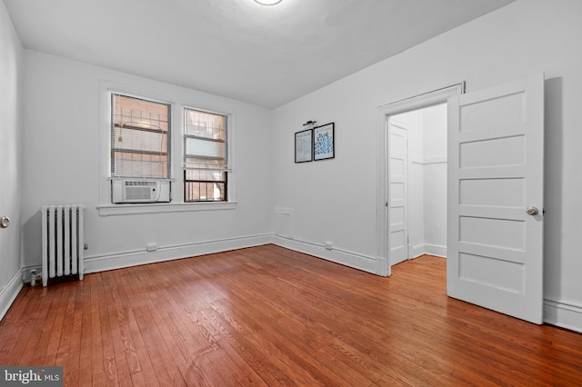 spare room with radiator heating unit, hardwood / wood-style floors, baseboards, and cooling unit