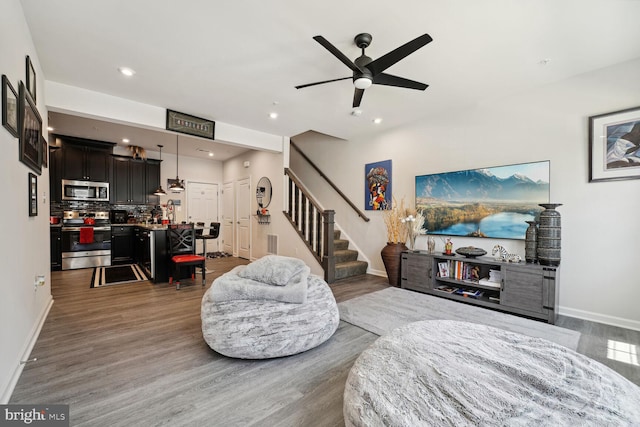 living room with baseboards, stairs, wood finished floors, a ceiling fan, and recessed lighting