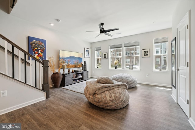 living room with stairway, wood finished floors, ceiling fan, and baseboards