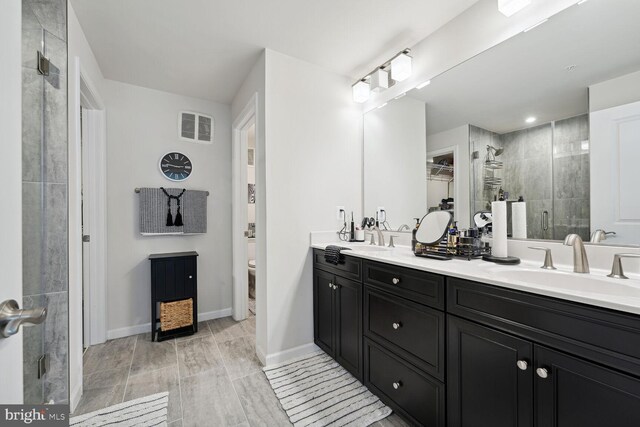 full bath featuring a stall shower, double vanity, toilet, and baseboards