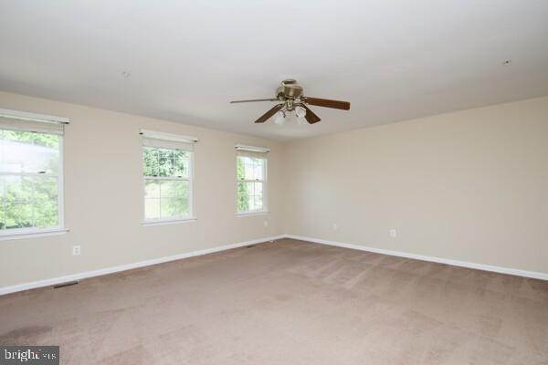 carpeted empty room featuring ceiling fan and baseboards