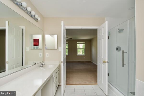 full bathroom featuring tile patterned floors, a shower stall, vanity, and baseboards