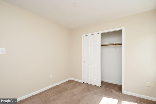 unfurnished bedroom with carpet flooring, baseboards, and a closet
