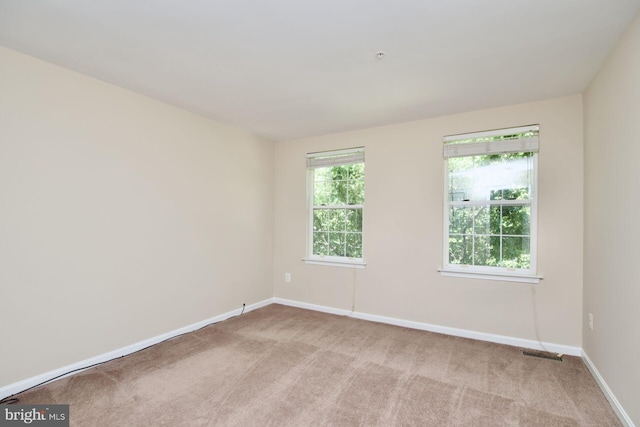 spare room featuring light colored carpet and baseboards
