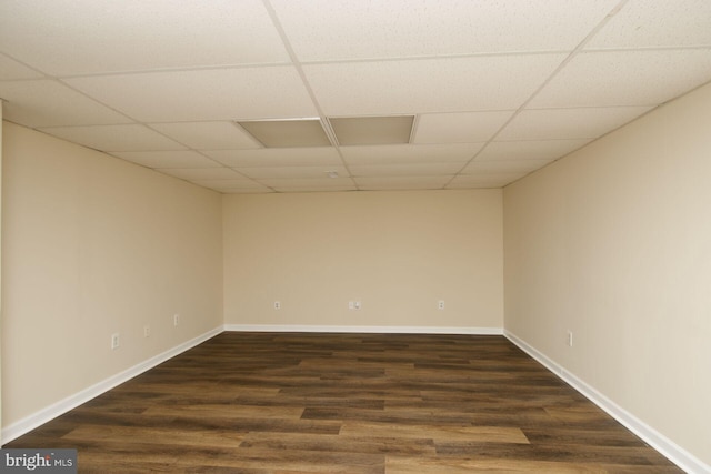 spare room featuring a paneled ceiling, dark wood-style floors, and baseboards