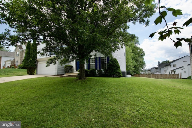 view of property hidden behind natural elements featuring driveway and central AC