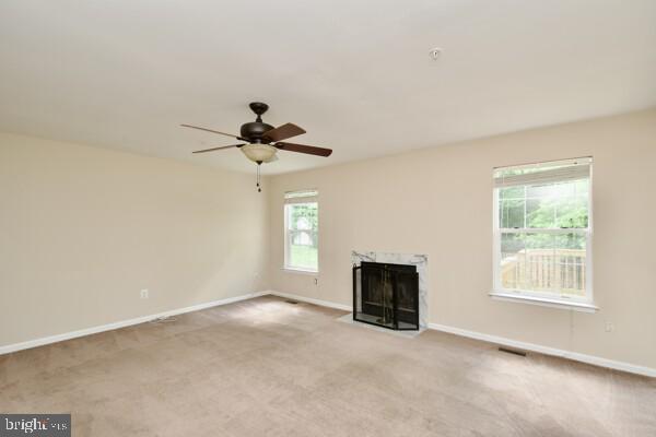 unfurnished living room with baseboards, ceiling fan, a premium fireplace, and carpet flooring
