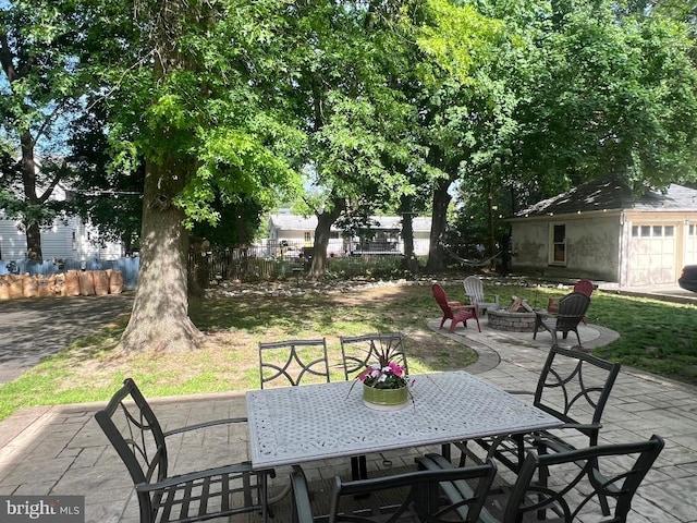 view of patio featuring a fire pit, outdoor dining space, fence, and an outbuilding
