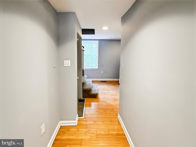 hall with light wood-type flooring and baseboards