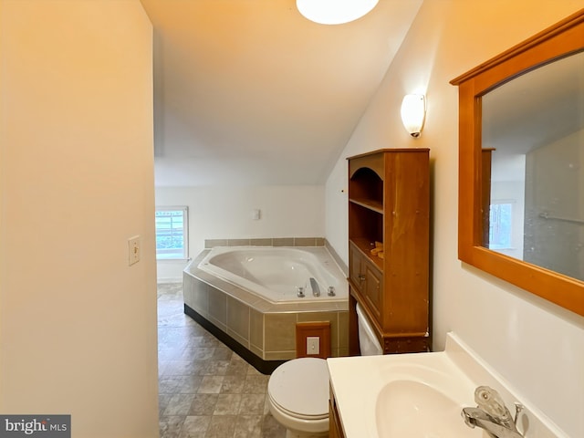 bathroom with a garden tub, vaulted ceiling, vanity, and toilet