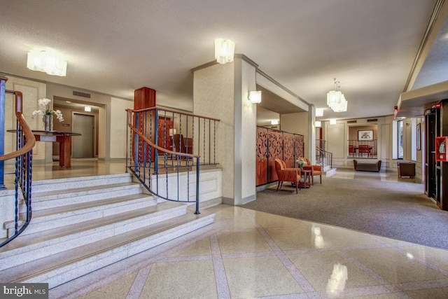 staircase featuring inlaid floor details, a chandelier, baseboards, and granite floors