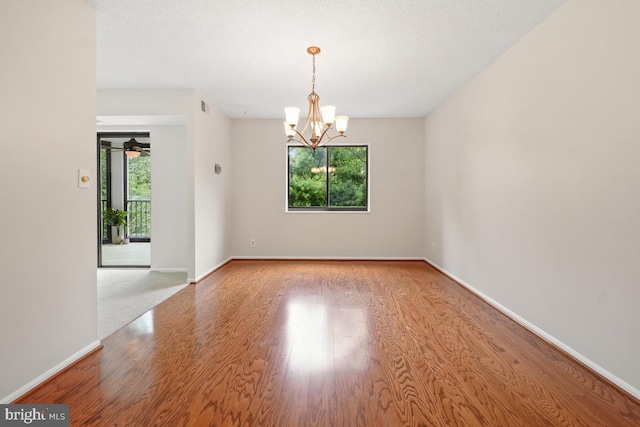 spare room with a chandelier, wood finished floors, and baseboards