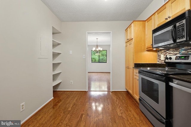 kitchen featuring stainless steel electric range oven, a chandelier, dark countertops, wood finished floors, and tasteful backsplash