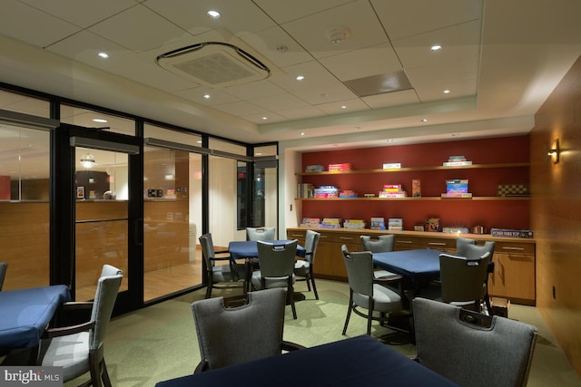 dining area featuring a tray ceiling, light colored carpet, and a drop ceiling