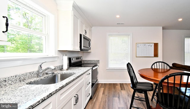 130 Schultz Rd, Sellersville, PA 18960 - kitchen featuring appliances with stainless steel finishes, a sink, wood finished floors, white cabinets, and light stone countertops