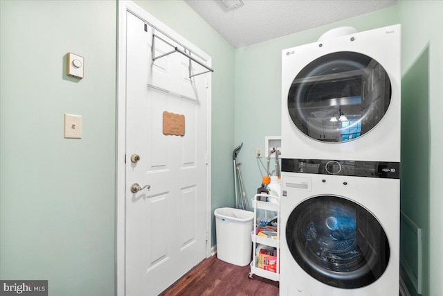 laundry room featuring stacked washer / dryer, dark wood-style flooring, and a textured ceiling