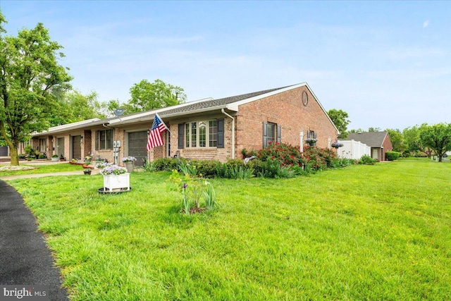 ranch-style home featuring brick siding, a front yard, and an attached garage
