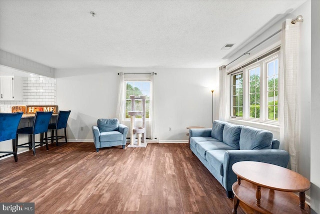 living room featuring dark wood-style floors, a textured ceiling, and baseboards