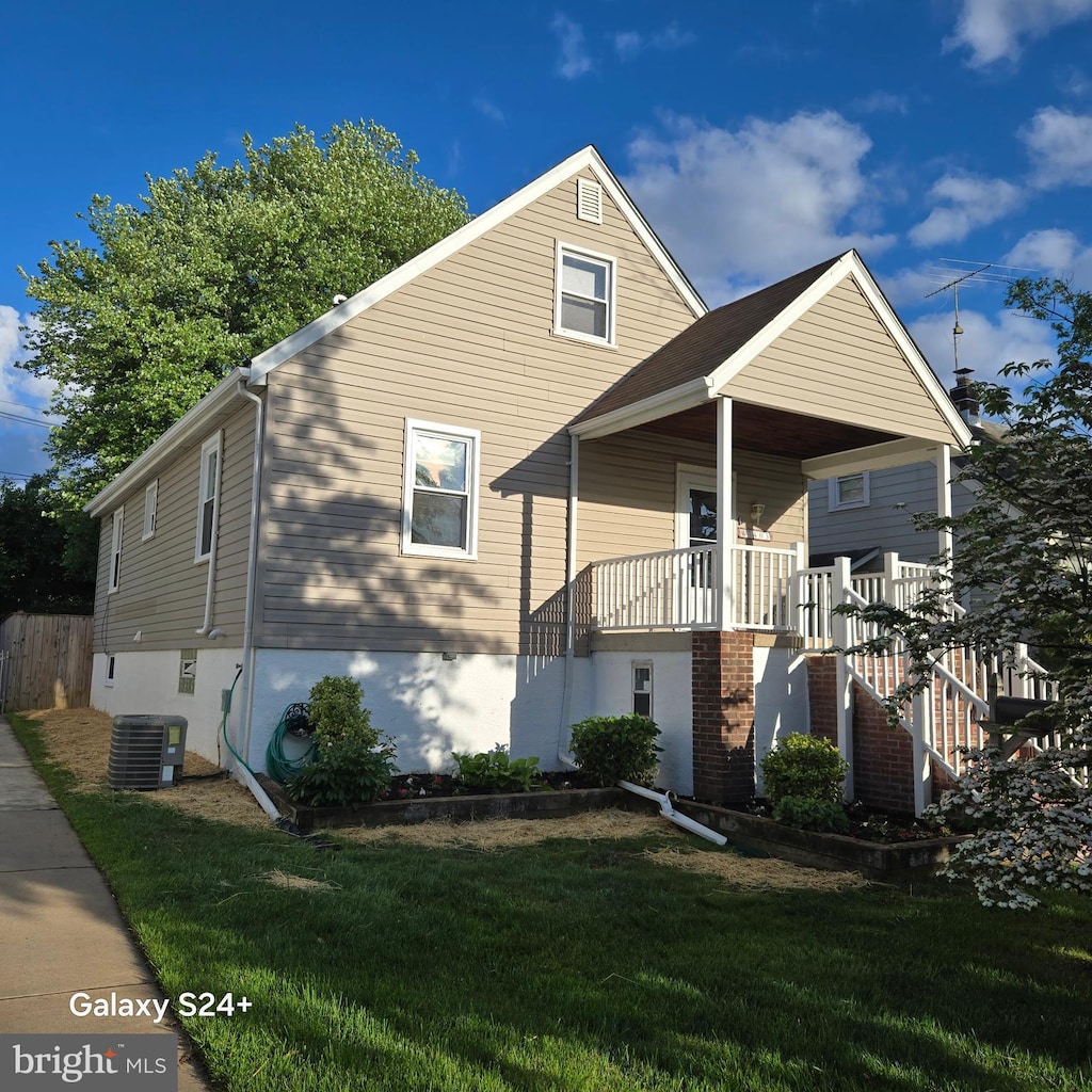 view of front of property with a front lawn, stairs, covered porch, and central AC