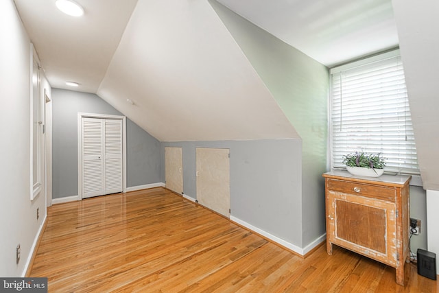 bonus room with light wood finished floors, lofted ceiling, and baseboards