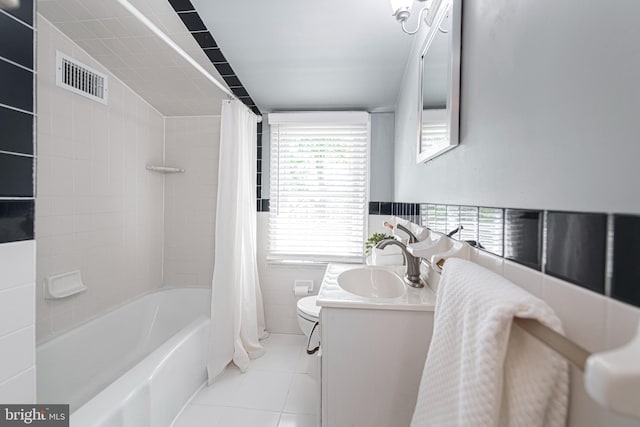 bathroom featuring tile patterned flooring, shower / tub combo with curtain, tile walls, vanity, and toilet