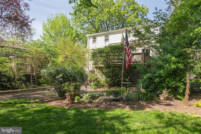 view of green lawn featuring a wooden deck and stairs