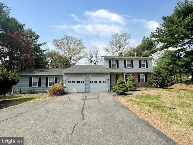 traditional-style home featuring an attached garage and asphalt driveway