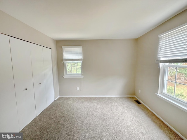 unfurnished bedroom with multiple windows, carpet floors, and a closet