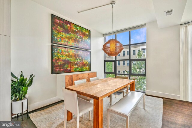 dining space with a wall of windows, wood finished floors, and baseboards