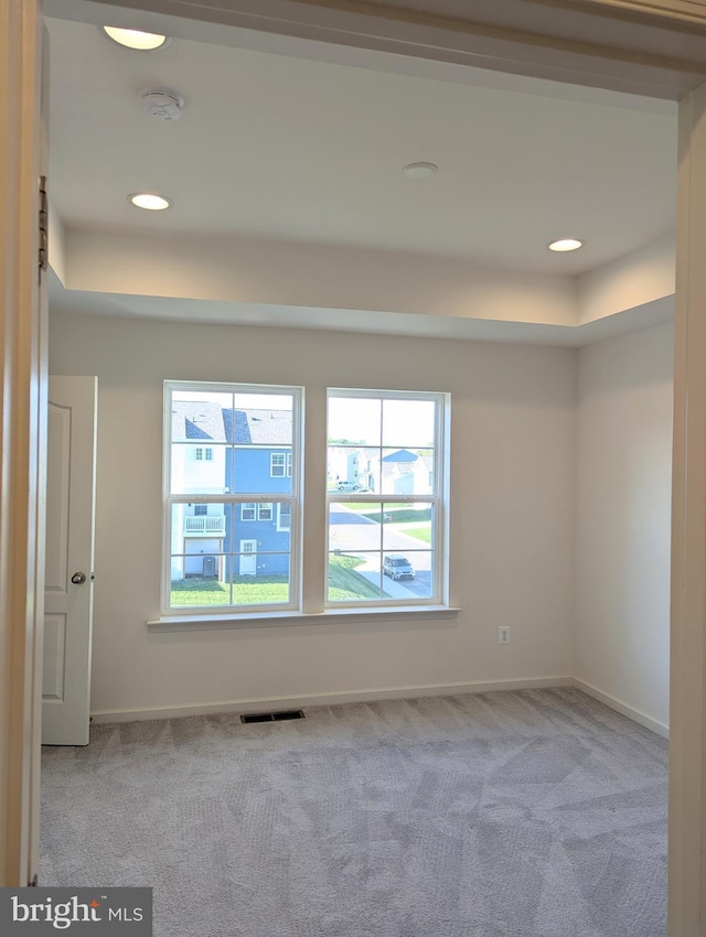 carpeted empty room with plenty of natural light, a smoke detector, baseboards, a raised ceiling, and recessed lighting