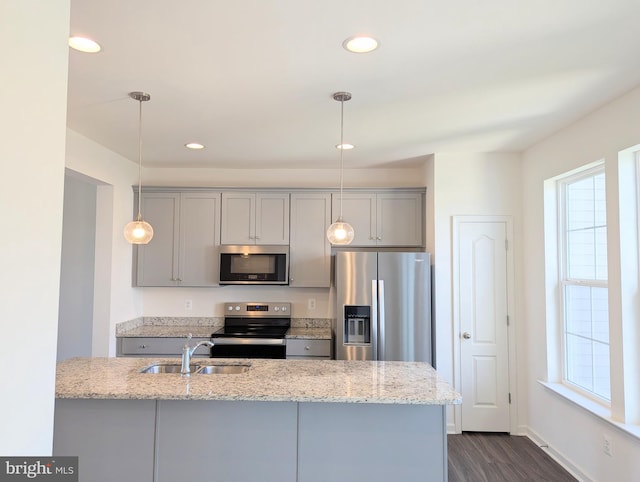 kitchen featuring appliances with stainless steel finishes, gray cabinetry, a sink, dark wood-type flooring, and healthy amount of natural light