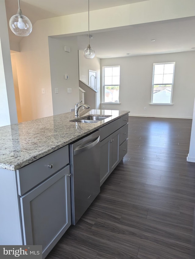 kitchen with dishwasher, a sink, dark wood-type flooring, light stone countertops, and hanging light fixtures