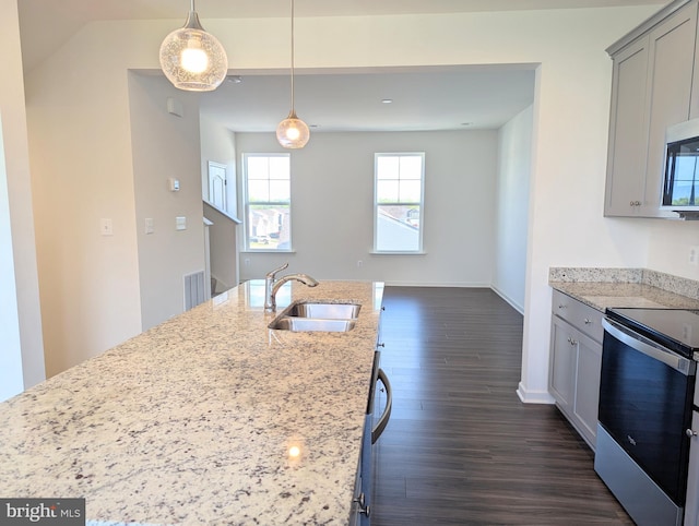 kitchen featuring a sink, appliances with stainless steel finishes, light stone countertops, dark wood-type flooring, and decorative light fixtures
